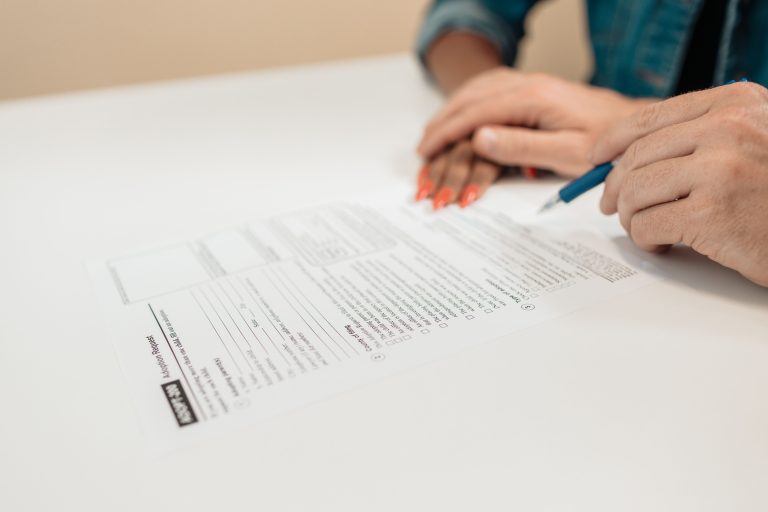 A hand holding a pen over legal papers on an office desk