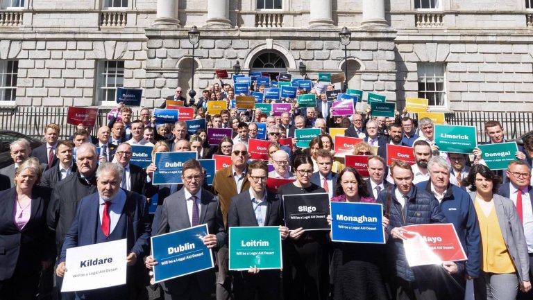 Solicitors gather outside a courthouse holding legal aid signs